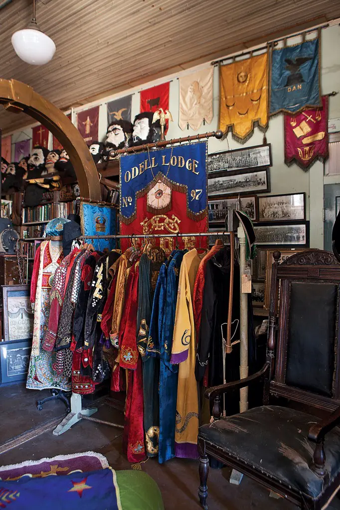 The lodge collection room, which also doubles as a guest bedroom for a brave occupant, brims with secret society robes and banners.