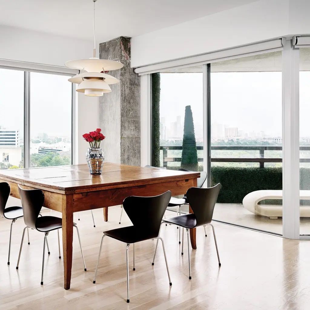 In the dining room, antique Italian walnut table from Chateau Domingue. Arne Jacobsen Series 7 chairs. Louis Poulsen lighting pendant. Vase is a flea-market find from Santa Fe.