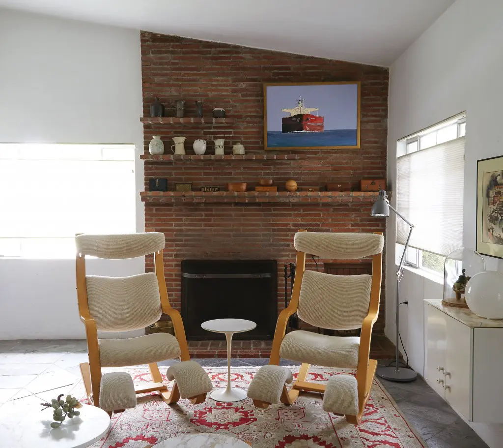 In the living room, a pair of Gravity Balans chairs designed by Peter Opsvik in 1983 for Stokke with Knoll wool fabric and a Saarinen side table for Knoll, both from Reeves Antiques.  The oil painting over fireplace — titled "Outbound" — is by Galveston Artist Leslie Sanders. The ceramics on the brick shelves were were made by Koush's mother.  