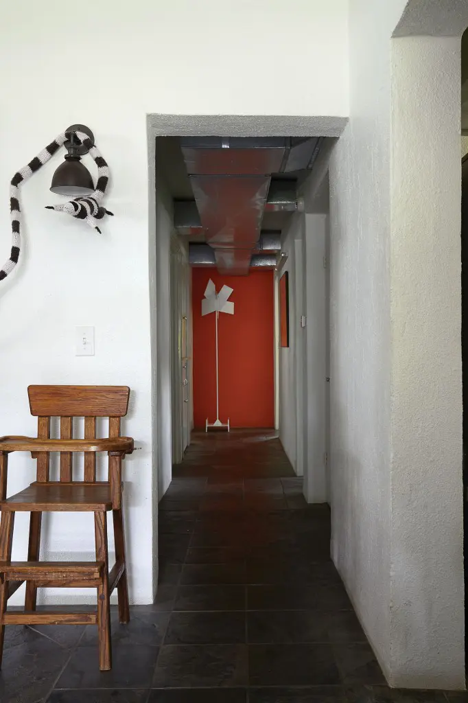 A steel sculpture rescued from a old Galleria-area house being demolished in the late 1990s sits at the far end the hall.  The oak highchair was built by Koush's grandfather and was used by Ben and his brother Greg as children.  The yarn and taxidermy artwork above it is by Houston artist Elaine Bradford.