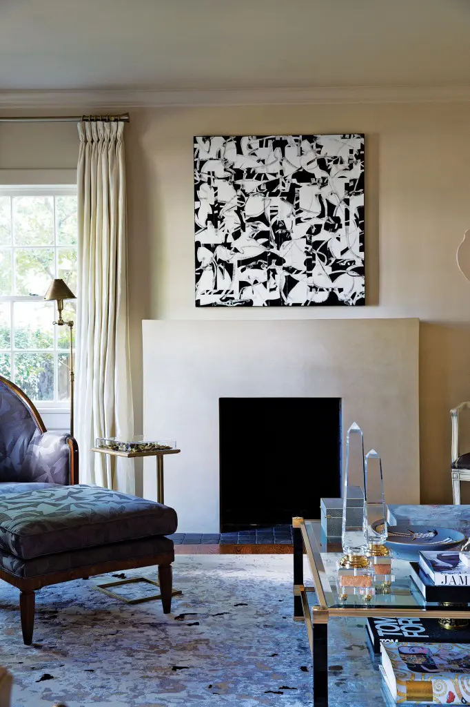 In the living room, a graphic Judith Foosaner painting from Laura Rathe Fine Art establishes the mood. Looke replaced a fussy mantel with this contemporary, streamlined version. Custom rug by Stark. 
