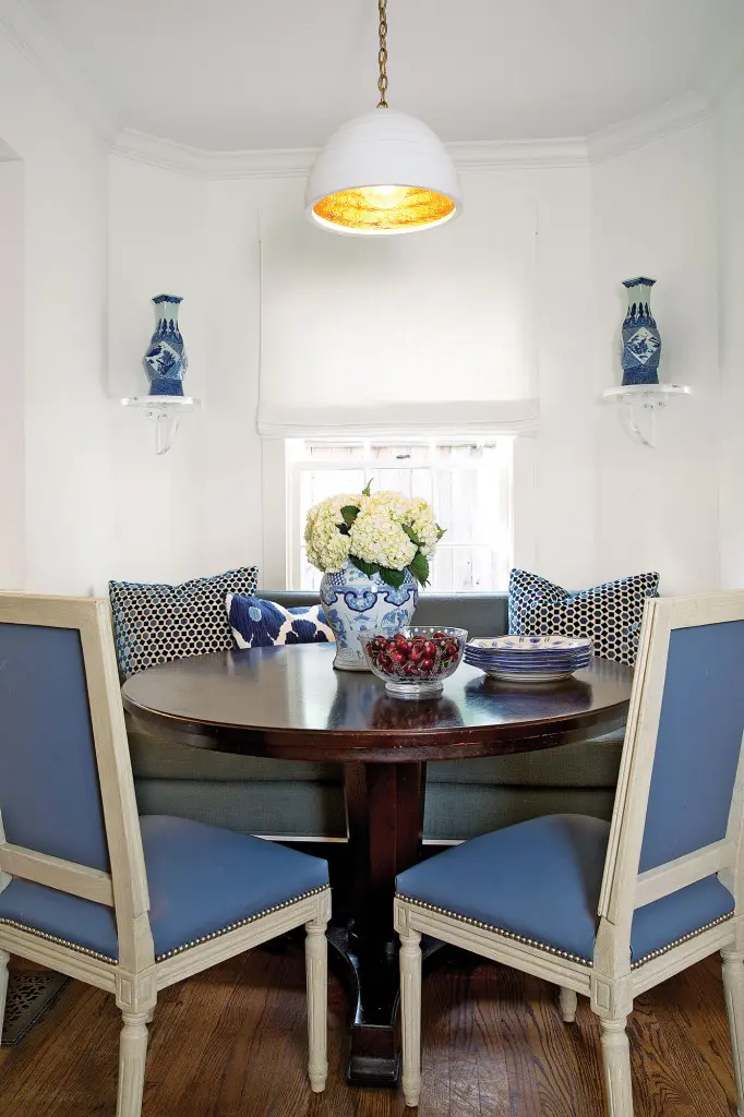 Looke crafted her breakfast room in the same blue and white hues as the kitchen. Lucite brackets from Wisteria hold decorative ginger jars. Table from Oly Studio. Pillows in Groundworks Lee Jofa and John Robshaw prints.
