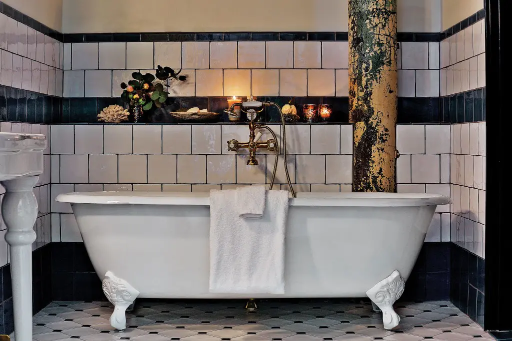 Hotel Emma’s guest bathrooms feature custom blue-and-cream tile with a rustic surface developed by Roman and Williams design firm.
