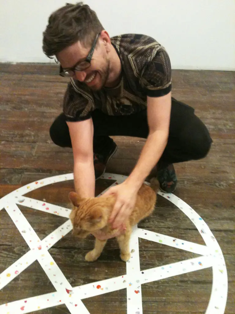 Mark Ponder's exhibition spilled from GalleryHomeland into project space, HomeCore. Shown: Ponder with Ike (the gallery's official mascot), patrolling a pentagram, which references the artist's exploration of world religions and belief systems.
