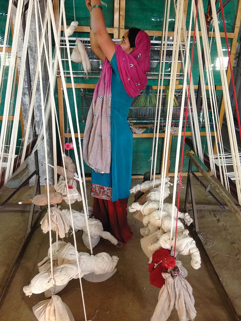 One of the weavers in Maheshwar, India setting up the wooden handloom to prepare for weaving.