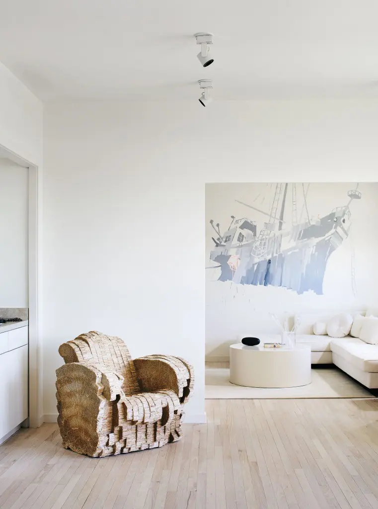 Architect Frank Gehry’s "Beaver chair," 1987, formed from cardboard, functions as a sculpture in Barbara Davis’ monochromatic living room.
Mie Olise’s wall painting references a metaphoric voyage. Nomade 2 sofa by Didier Gomez from Ligne
Roset. The ottoman is a timeless design Davis has
owned for several decade, now painted to match the interiors.
