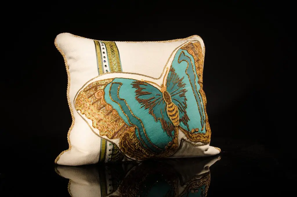 Hand-beaded turquoise and green butterfly, appliqued onto linen; trimmed with gold braid, metal antique ribbon and vintage deco glass beads; cream silk back with hand-beaded insect and vintage French ribbons, $2,200