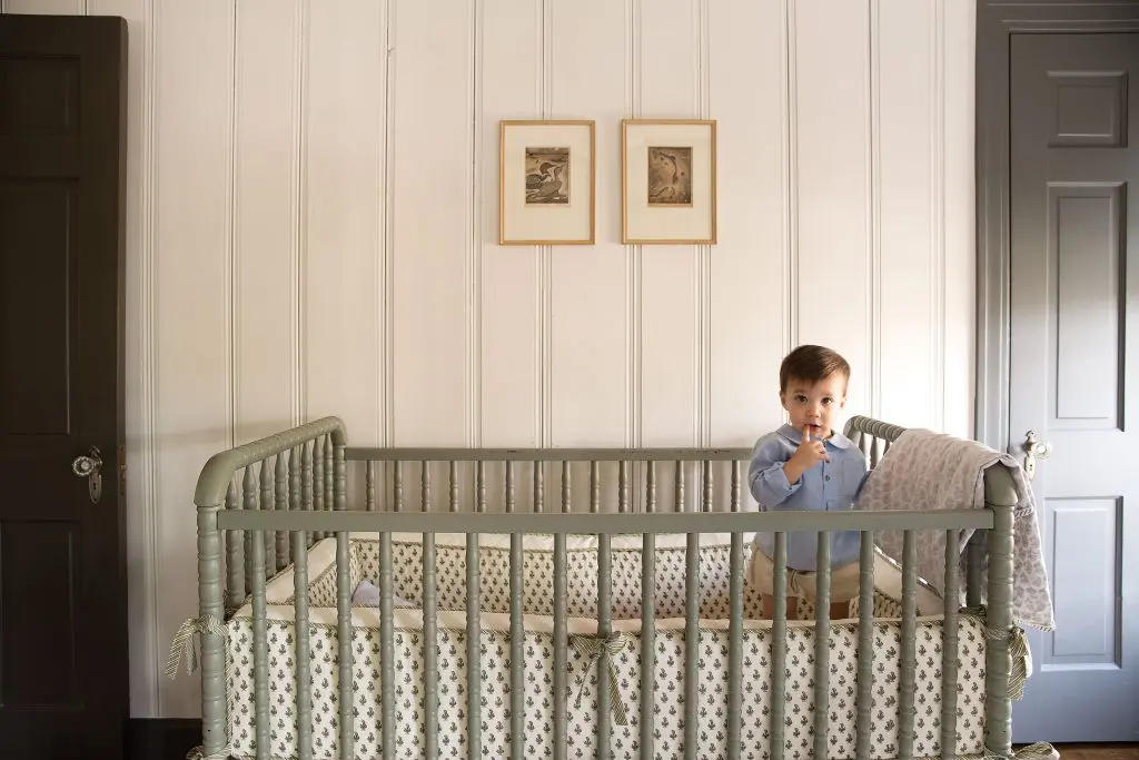 Theo awakes from his morning nap in a Jenny
Lind crib with custom Mela & Roam bedding.