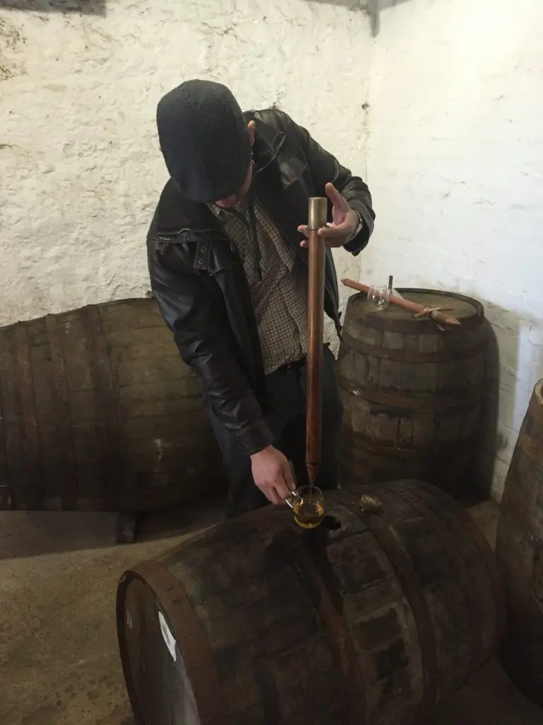 Jessey Qi tasting from the barrel at Laphroaig. (Photo by Bobby Heugel)