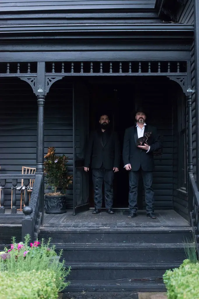 Chad and Richard Bettinger with Coco, on the porch of the 19rh-century Black House