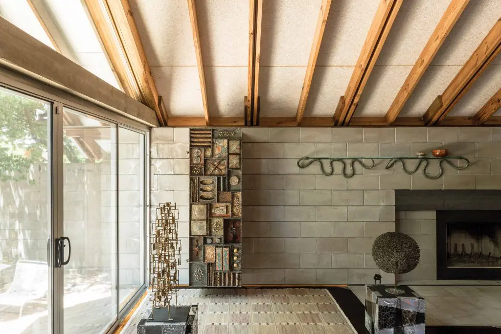 Three American masters rule in a corner of the light-flooded living room. From left, Harry
Bertoia’s sculptures, Multi-plane and Bush, rest on Paul Evans Argente cubes. Suspended from the concrete-block wall, Paul Evans’ tour de force Forge Front cabinet is a study in metal artistry. Judy Kensley McKie’s sinuous metal serpentine shelf activates the fireplace.