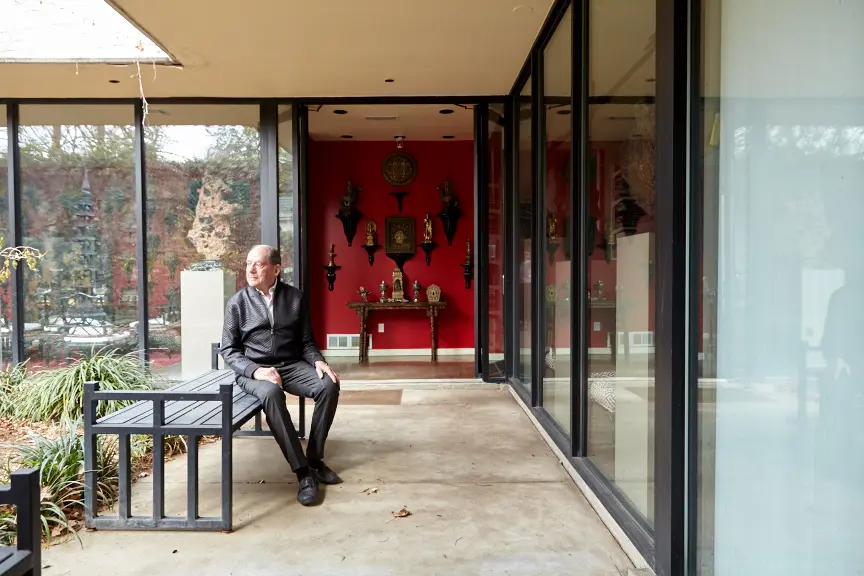 Loyd Taylor in the front courtyard. In the entry, objects from Tibet and India surround a Ming Dynasty wine table.