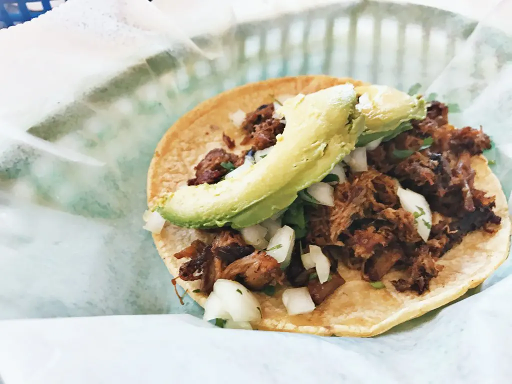Tacodeli's  El Conquistador features roasted organic pork shoulder, chile pasilla sauce, avocado, cilantro, and onion.