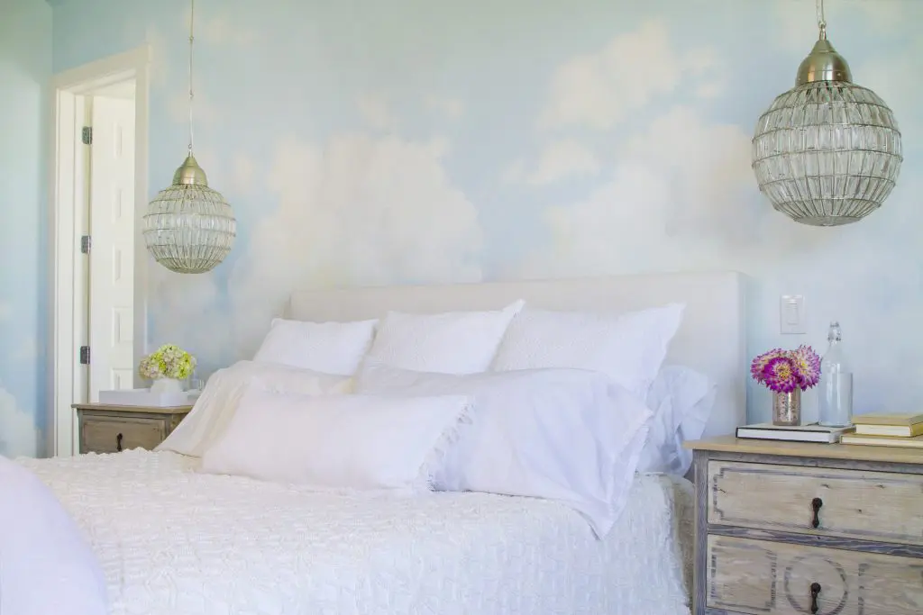 In the master bedroom, custom hand painted cloudscape by Peggy Jones; Wisteria Montgolfier chandeliers; Dressers by Customfurniturela; Room & Board Wyatt California King Bed in Sunbrella canvas white fabric. (Photo by Manny Rodriguez)