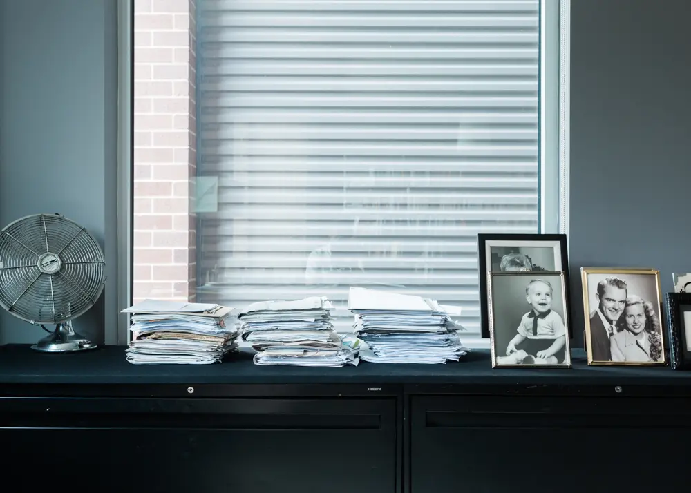 Atop a filing cabinet that holds 28 feet of storage, a vintage Cinni fan, files bursting with archival research, the author’s baby picture, and his parents’ engagement photo.