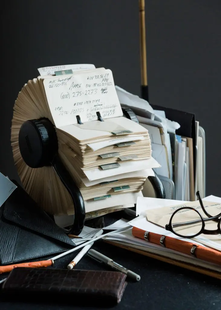 Desk corner with alligator Alexandra Knight magnifying glass (a gift from Lynn Wyatt), custom-made glasses by Maison Bonnet in Paris, a Louis Vuitton alligator agenda, and well-thumbed Rolodex. (Photo by Max Burkhalter)