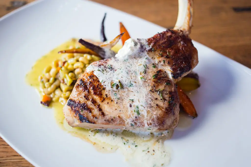The sous vide pork chop is served with lady cream peas, glazed rainbow carrots. 