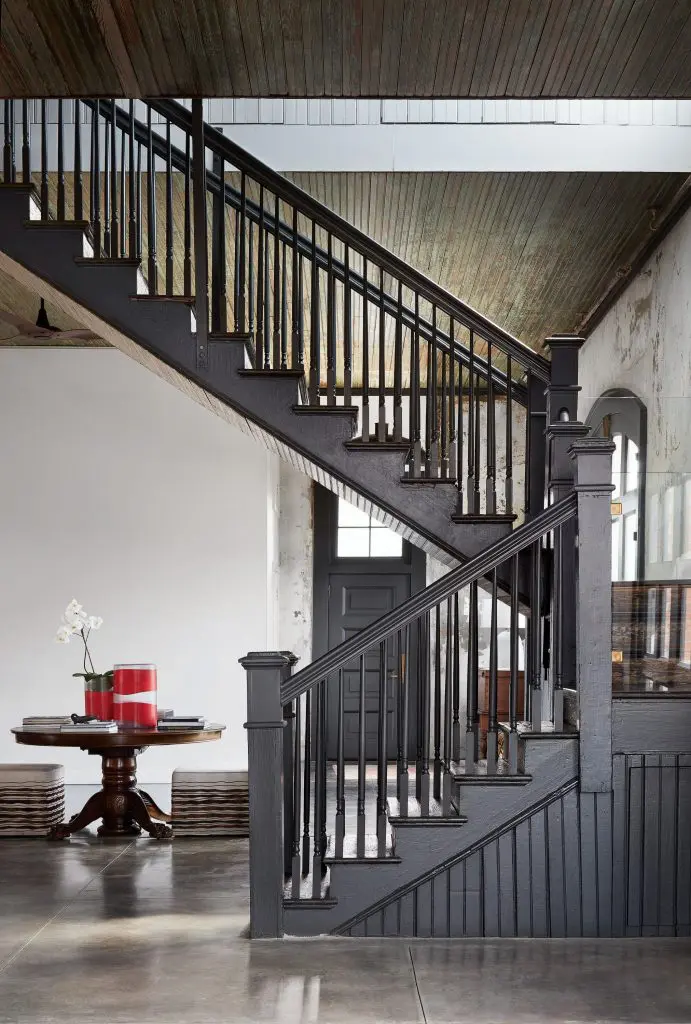 The original staircase has been updated with glass panels on the landing. Original green beadboard ceilings. Red Holly Hunt vases on family heirloom table. Upholstered cubes from Area. 