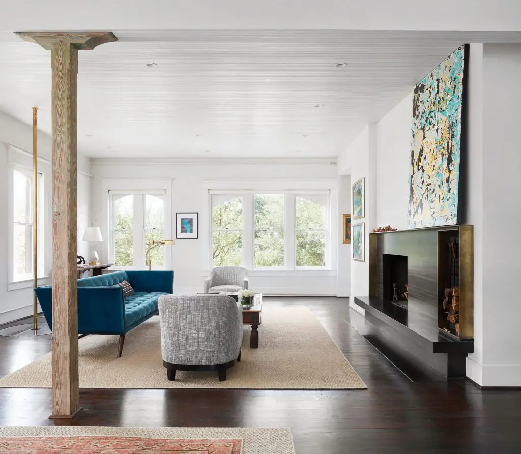Upstairs, custom sofa in Holly Hunt Great Plains. Original beadboard ceiling was painted white. Custom brass fireplace details created by James Dawson. Original wood pillar. Antique brass fire pole. 