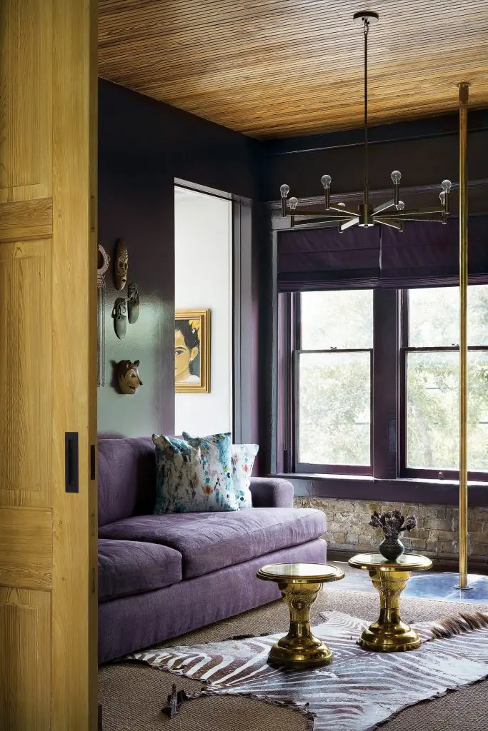 In the library, custom sofa covered in Holly Hunt velvet. Vintage brass tables. African zebra-hide rug. Antique brass fire pole. Vintage painting. 