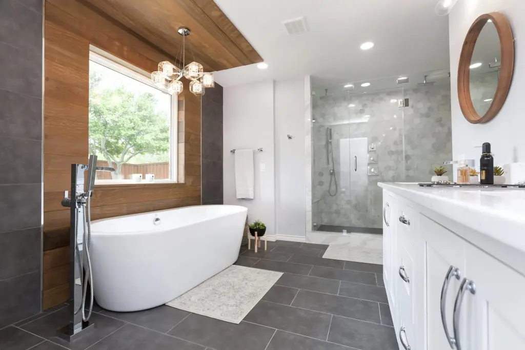This modern bathroom remodel combines marble tiles with gorgeous wood accent wall that adds warmth to the modern space. Custom vanity and concrete-like porcelain flooring tiles to complete the modern look and feel. 