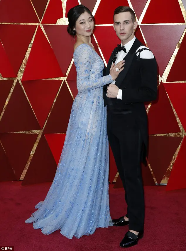 Mirai Nagasu wore a gown designed by Tadashi Shoji at the Academy Awards. Adam Rippon wore a shoulderless tux with a harness designed by Moschino's Jeremy Scott.