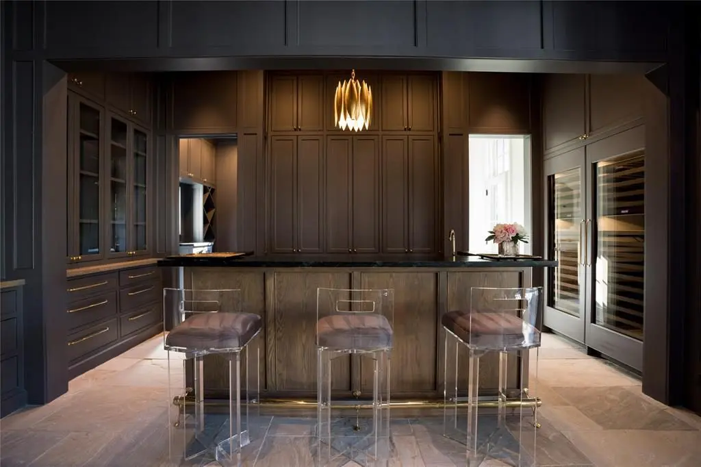 The wet bar with a white oak inset cabinet has a brass faucet and deep drawers, ideal for bottle storage. 