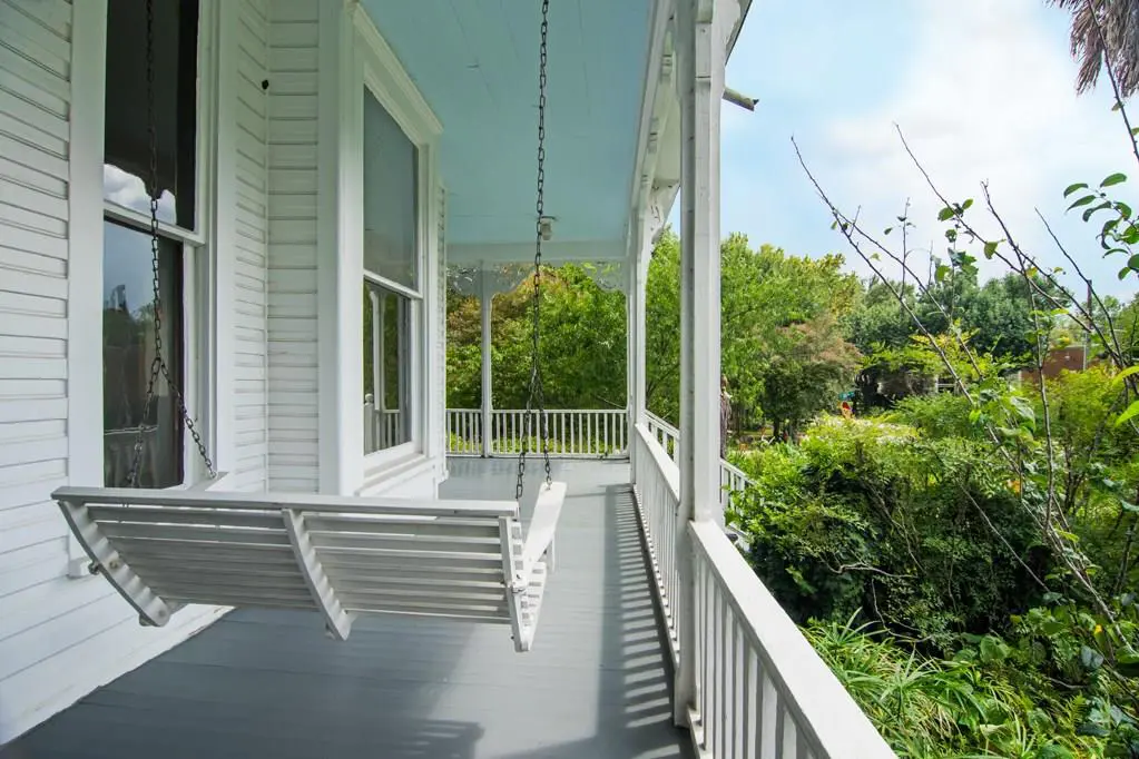 The wrap around porch features traditional paint blue ceilings and a porch swing. 