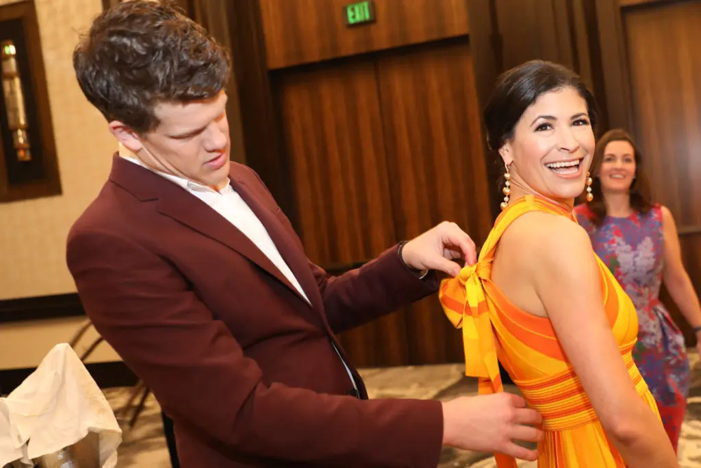 Carolina Herrera creative director Wes Gordon shows Best Dressed honoree Kristy Bradshaw how to tie the bow on her Carolina Herrera sundress. (Photo by Priscilla Dickson Photography)