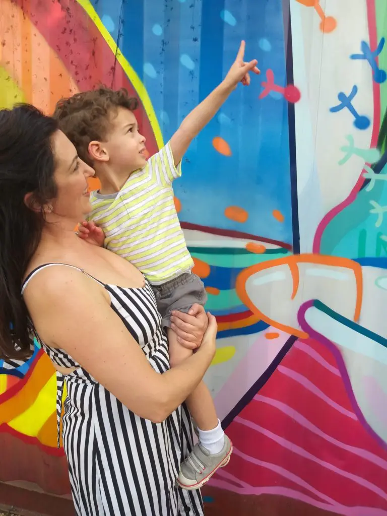 Sarah Bray and son, Xavi, admire DUAL's aerosol prowess. As part of the American Wind Energy Conference in Houston, AWEA and Bray's firm, Innovant PR, underwrote this mural. Bar Boheme donated the site. (Photo by CDA) 