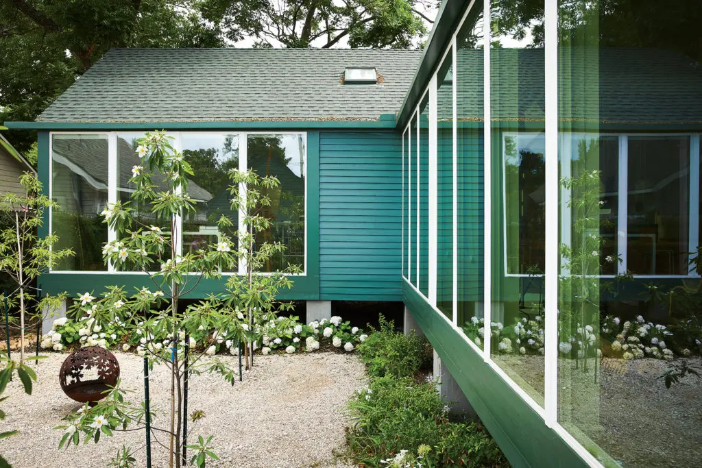 Modular windows line the garden elevations of the house. Roof and walls are dark green to blend with foliage and conceal staining. White-blossoming Gordlinia trees will form an arbor in the courtyard when full grown. White, Blushing Bride hydrangeas on far wall. Plants on long side are all white-flowering and include agrapanthus, amaryllis, cat’s whisker, gardenia, ground orchid, lantana, dwarf loropetalum, narcissus, plumbago, Pope John Paul tea rose, wood sorrel, and yarrow. (Photo by Pär Bengtsson)