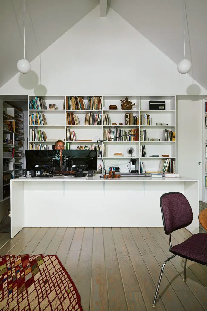Ben works in his storefront studio at a large melamine table he designed. Kelvin Edge black task lamp was originally designed by Antonio Citterio for Flos in 2015. Ceiling pendants are inexpansive frosted glass globes from Progress Lighting. Lossanges wool carpet was originally designed by the Bouroullec Brothers for Nanimarquina in 2011. Carpet and task lamp from Kuhl-Linscomb. Pencil holder on the desk was made by Ben’s mom for her father. (Photo by Pär Bengtsson)