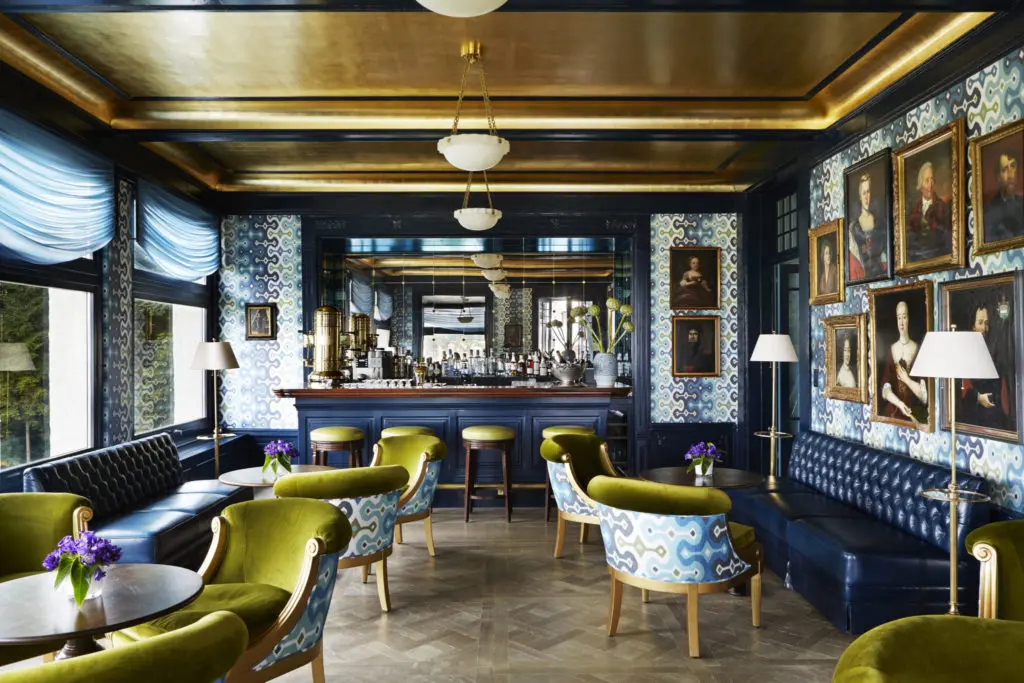 At Chateau Gutsch in Lucerne, the Gütsch bar—or Ancestor Bar as Bullard prefers to call it—was hung in his Adras Ikat wallpaper for Schumacher, upon which he grouped antique oil paintings from the hotel’s original collection. The ceiling was gold-leafed to reflect the sparkling city lights at night while the windows that surround the bar look out to spectacular lake views. 