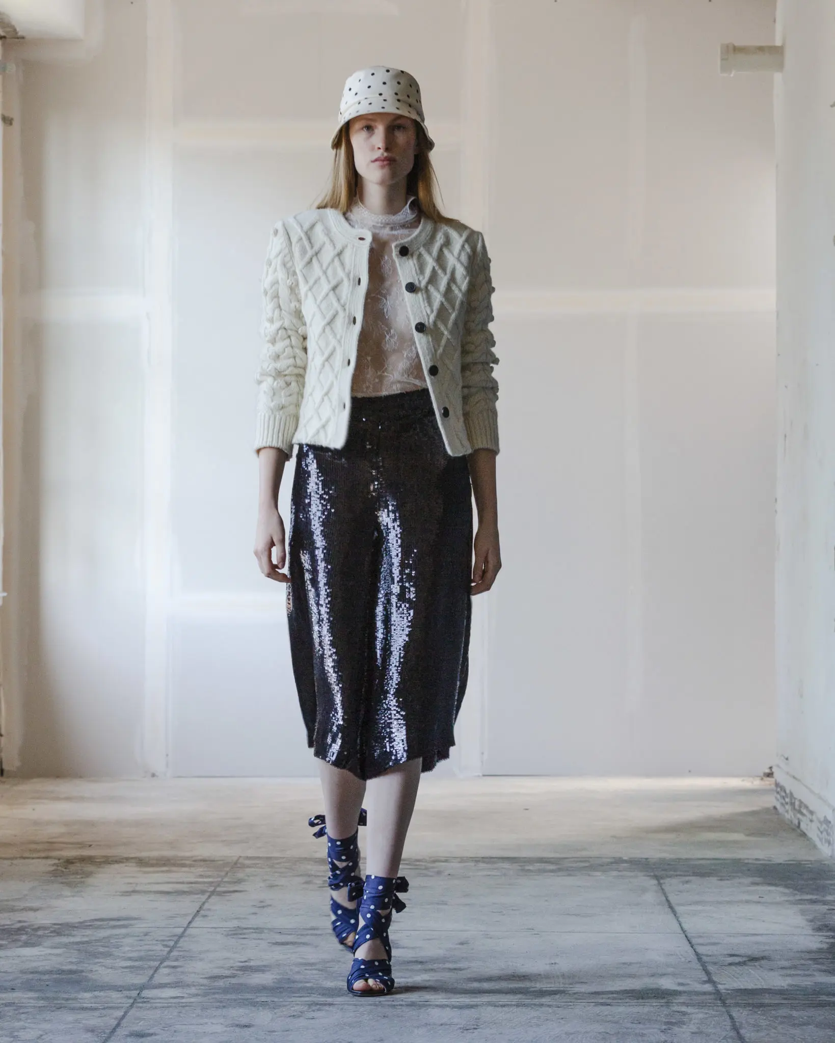 Adam Lippes ivory hand-knit Scottish cardigan, ivory Chantilly lace turtleneck, hand-embroidered black sequin culotte, navy silk twill ankle wrap heel. (Photo courtesy of Adam Lippes)