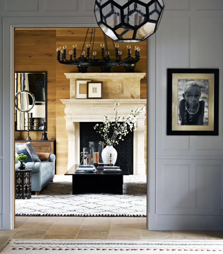 In a Malibu project, entry foyer walls are painted a pale egg blue from Benjamin Moore’s historic colors, giving way to the wood-planked living room. An African child’s portrait by Lyndie Benson makes a striking statement on the paneling. 