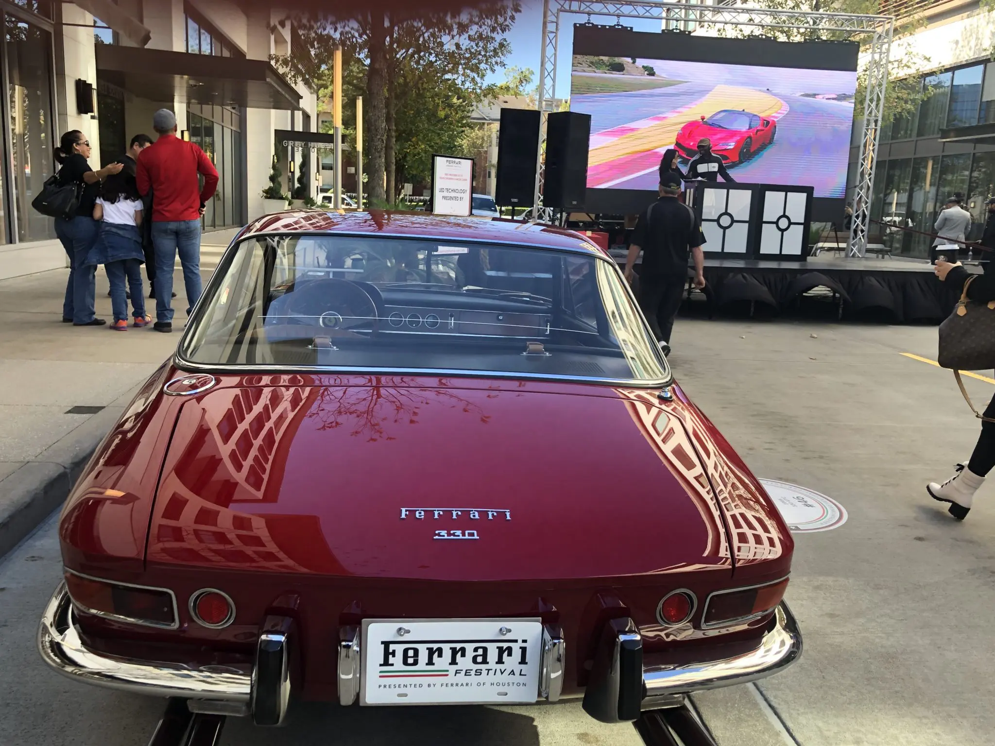 A classic Ferrari on the pavement and a reace car on the screen (Photo by Shelby Hodge)