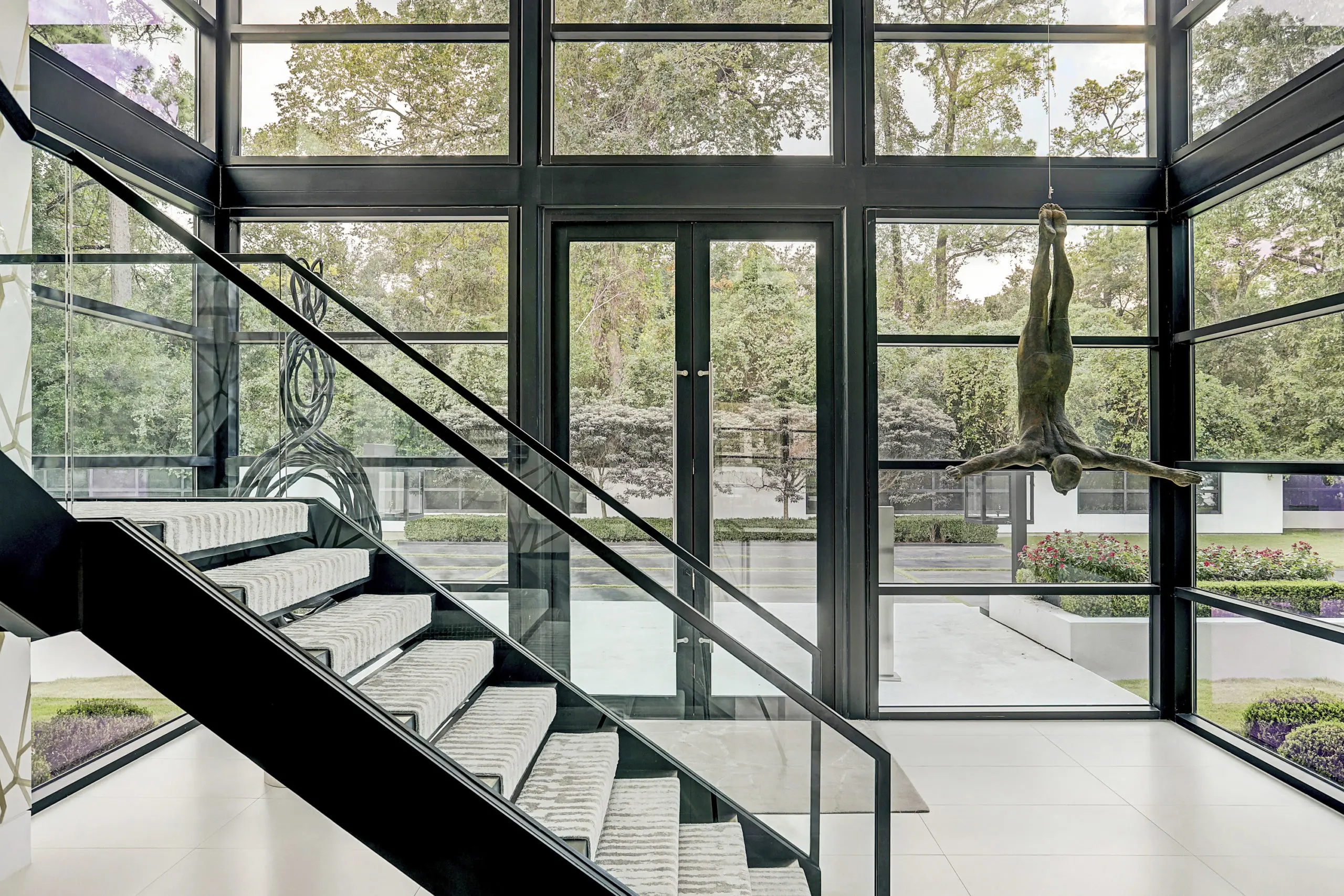 The entry opens to a soaring foyer and one of two custom iron and glass staircases. (Photo by TK Images)