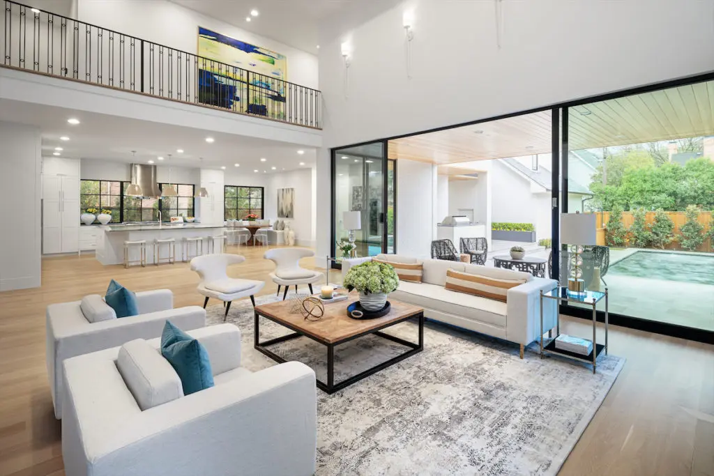 An open living area includes a glass wall that can slide open to reveal a screened-in outdoor living area. 