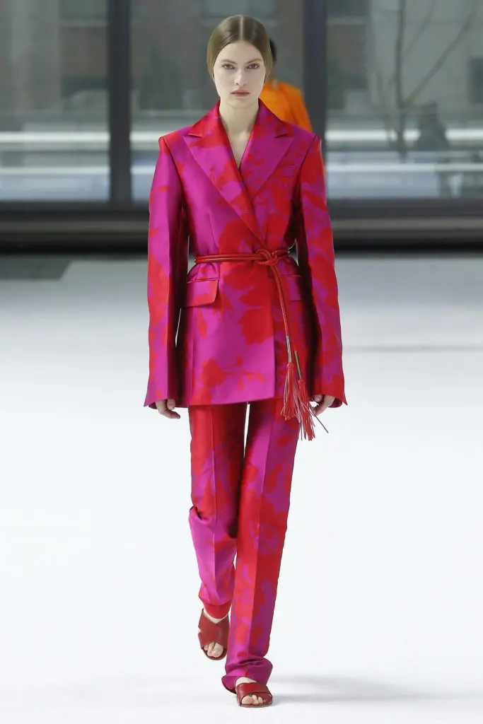Carolina fuchsia floral jacquard notched lapel one-button jacket and straight leg pant, imperial red tubular belt, red flat sandals. (Photo courtesy of Carolina Herrera)