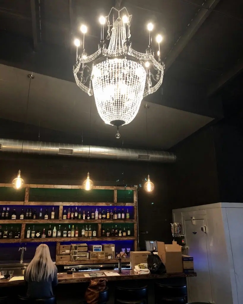 Tulane's black box style interior with purple and green back-lit bar and sparkling chandelier. 