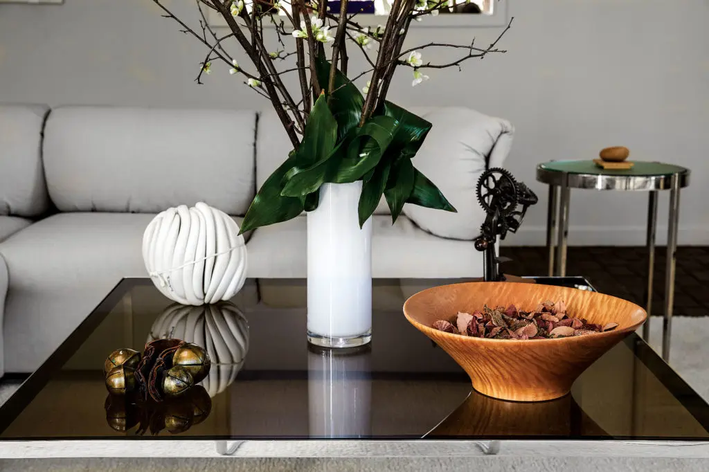 A Walsh tablescape, unchanged since the 1980s, with sleigh bells from her Sioux Falls childhood, a gift to the homeowners, a ceramic sculpture, and turned-wood bowl. Custom side table by Brochsteins. “Sally is very much here,” says Raymond of these interiors. (Photo by Pär Bengtsson)