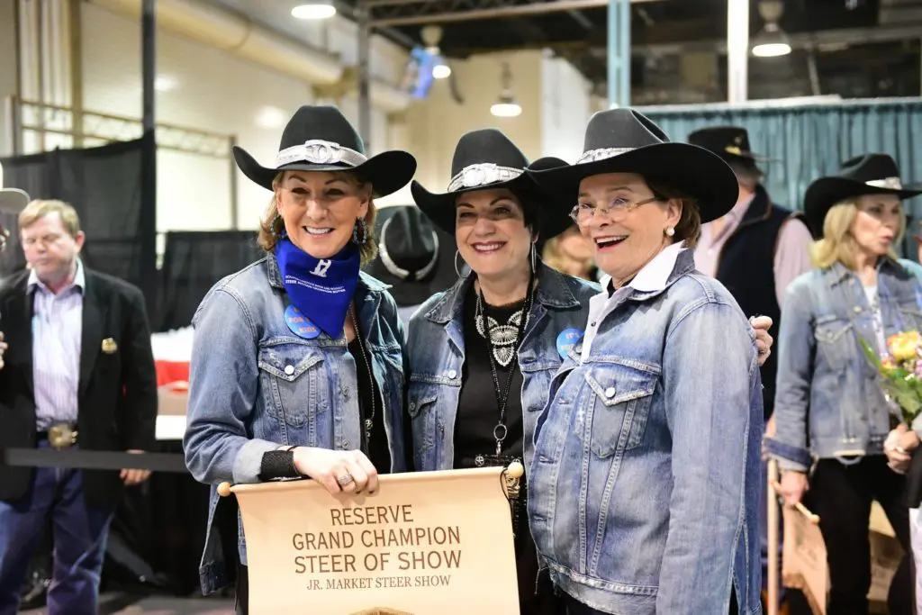 Champagne Cowgirls Shelley Reeves, Ellie Francisco, and Bobbie Nau celebrate the team's purchase of the 2019 Reserve Grand Champion