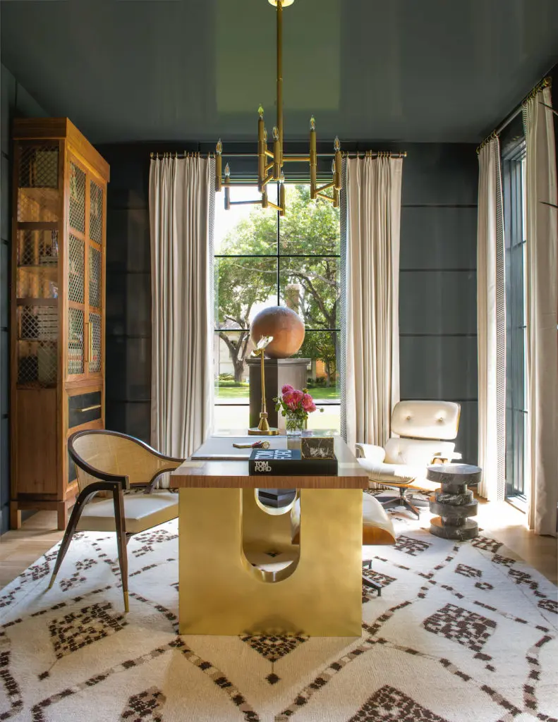 Designer Philip Thomas Vanderford gives the study a clubby feel with rich custom walnut-and-brass bookcase towers and desk, and creamy leather chairs by Edward Wormley for Baker and Eames. The dark, high-gloss ceiling and walls add reflected light; the Kelly Wearstler side table from Allan Knight and hand-knotted Abrash rug lend texture. Ralph Lauren for Visual Comfort light fixture. Antique terra-cotta garden-ball sculpture. (Photo by Costa Christ Media)