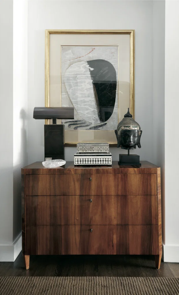 George Cameron Nash, published May 2017. Interior architecture Neal Stewart. Photographed by Lisa Petrole. In the entry hall of George Cameron Nash and Mark Williams' high-rise home, Biedermeier chest, Siamese Buddha, Moroccan inlay boxes, Karl Springer lamp, and a painting purchased in Santa Fe.