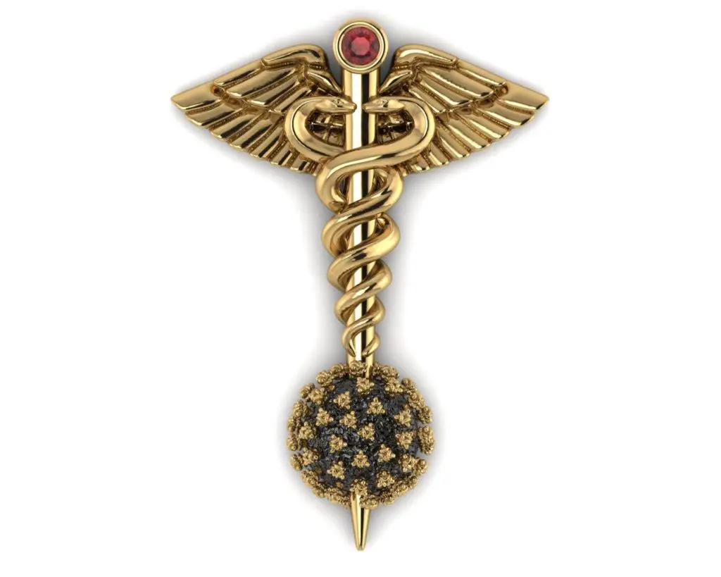 The sterling silver pin, dipped in 18k gold features the familiar caduceus with its intertwined snakes and wings topped with a deep red garnet.