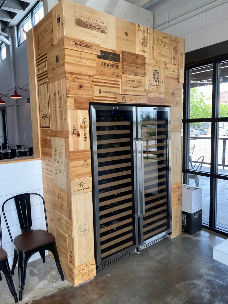 The wine cooler at Porta'Vino is framed in panels from wine boxes. Prices by the bottle only are said to be less than retail across the city. (Photo by Shelby Hodge)