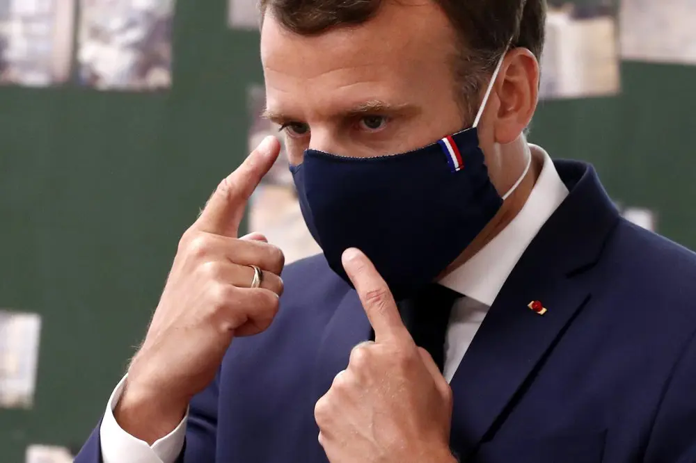 French president Macron points to his new face mask on his visit to a school in Poissy, France. (Photo by Ian Langsdon, pool photographer.)