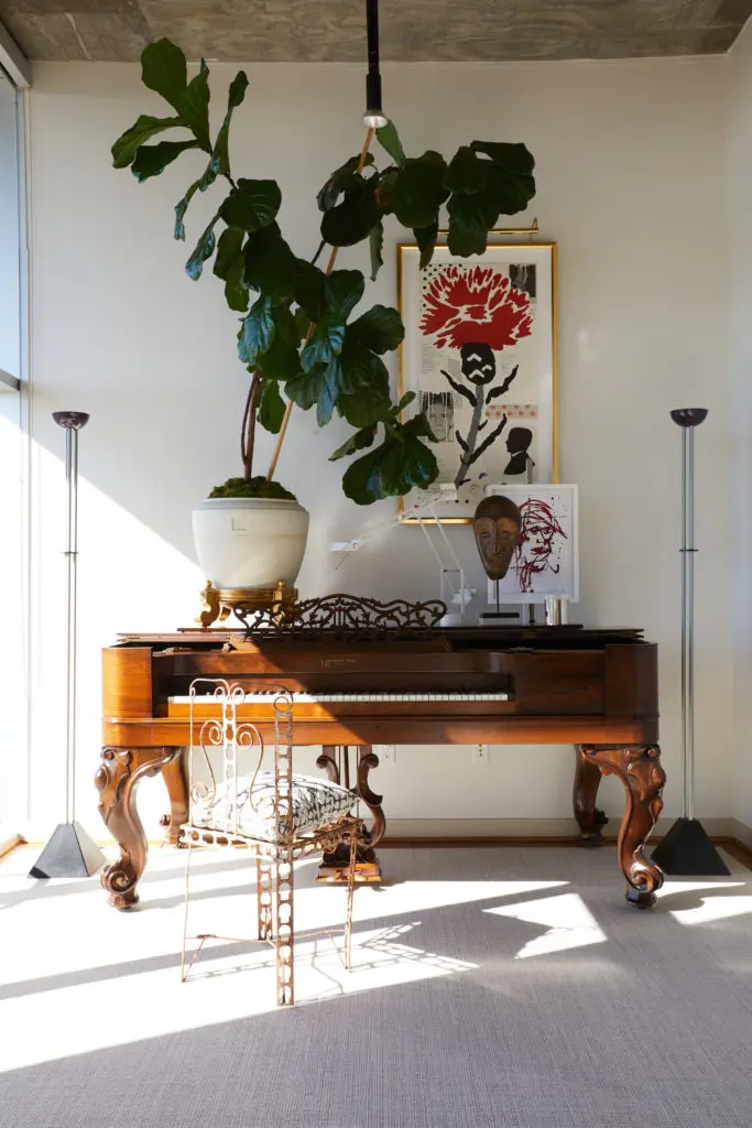 Christopher Alexander experiments with scale and composition in a vignette that includes an antique piano. Vintage Tizio table lamp and a pair of Ron Rezik floor lamps. Large lithograph by Donald Baechler. Small red India ink portrait by South African artist BJ Broekhuizen. Vintage garden chair from Round Top with Fortuny Pillow.  (Photo by Pär Bengtsson)