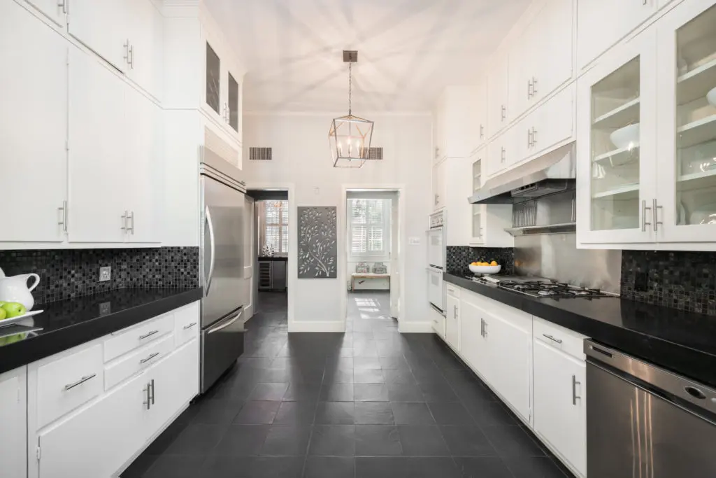Kitchen features original cabinetry with updated hardware, slate flooring, concrete countertops, complementary glass mosaic tile backsplash (Photo by Vlady Ambia)