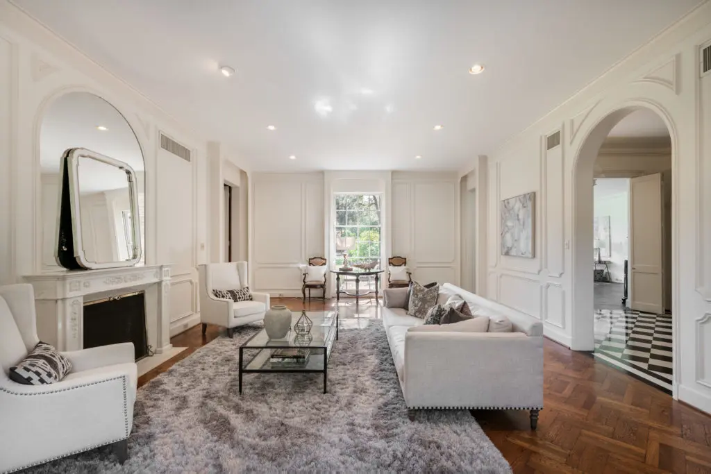 The formal living room features a grand marble fireplace, herringbone hardwood flooring, original triple hung windows, high ceilings and views of gardens. (Photo by Vlady Ambia)
